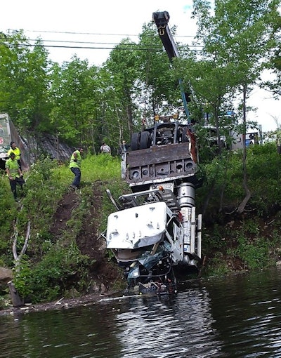 Wrecker workers in yellow safety shirts pull the damaged Mack daycab out of the Harriman Reservoir
