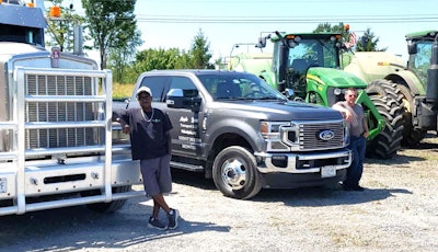 Owner-op Andrew Gockley (left) at Maple Lane's appreciation event earlier this year, leaning against his 2003 Kenworth W900L. On the right, his father, Galen Gockley, and the 2021 F350 Ford he owns, also leased to Maple Lane and hauling cars.