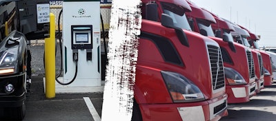 A Class 8 EV charger and used trucks lined up at a dealer