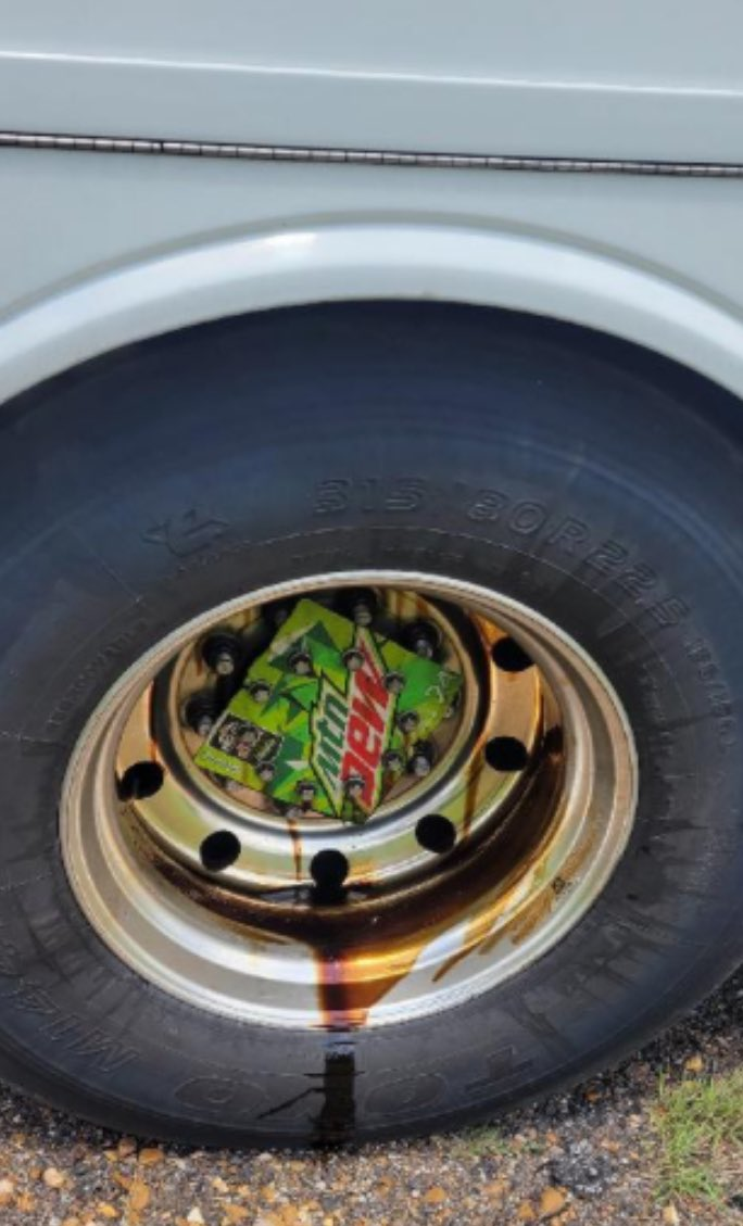 Semi-truck tire with part of a Mountain Dew box as a wheel cover allowing a wheel seal to leak oil,