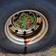 Semi-truck tire with part of a Mountain Dew box as a wheel cover allowing a wheel seal to leak oil,