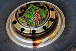 Semi-truck tire with part of a Mountain Dew box as a wheel cover allowing a wheel seal to leak oil,