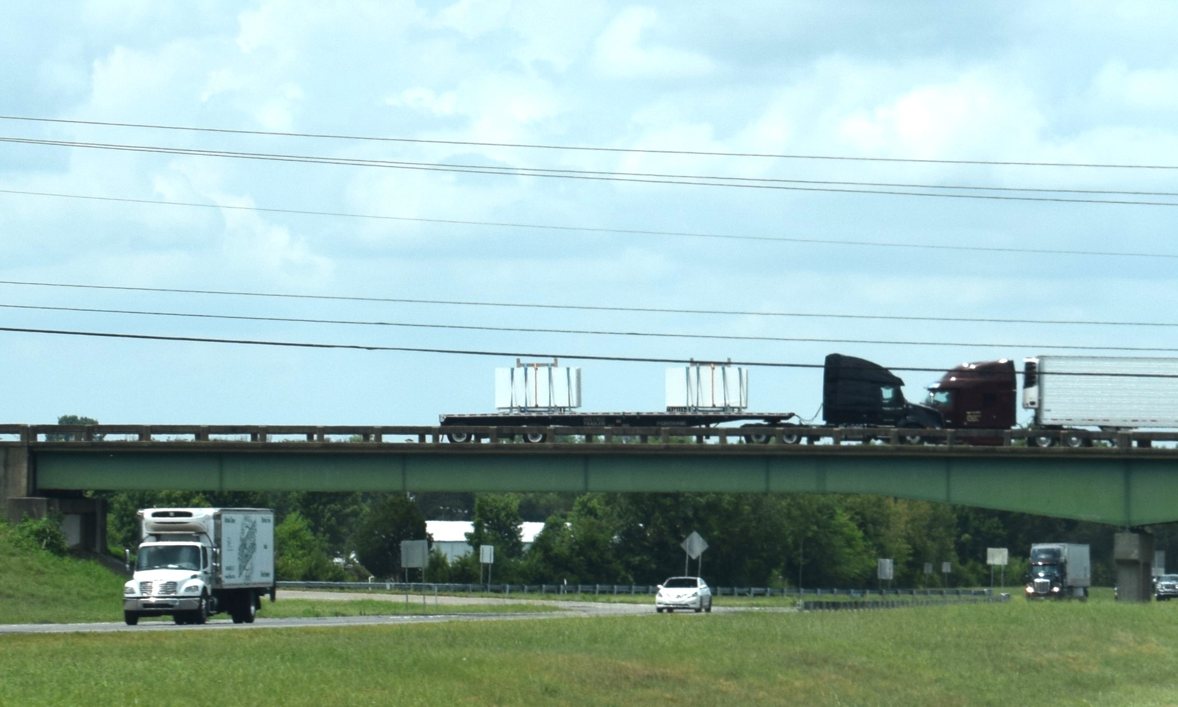 two semi-trucks on a bridge over interstate