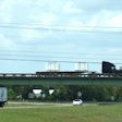 two semi-trucks on a bridge over interstate