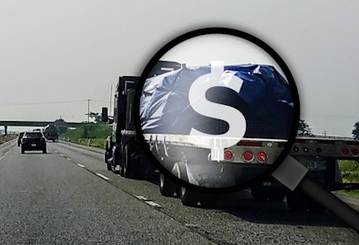 Flatbed on highway with magnifying glass, dollar sign