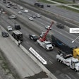 This aerial view of the crash site on I-35 shows the tractor-trailer at its final rest position. Other crash-involved vehicles can be seen within the roadway behind the combination vehicle.