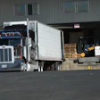 Semi-truck at warehouse loading dock with forklift and palletized cargo