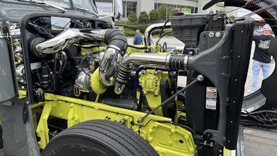 The Cat C15 is coupled with an 18-speed transmission. The bright yellow paint and stainless work on the engine stand out against the dark gray of most of the rig.