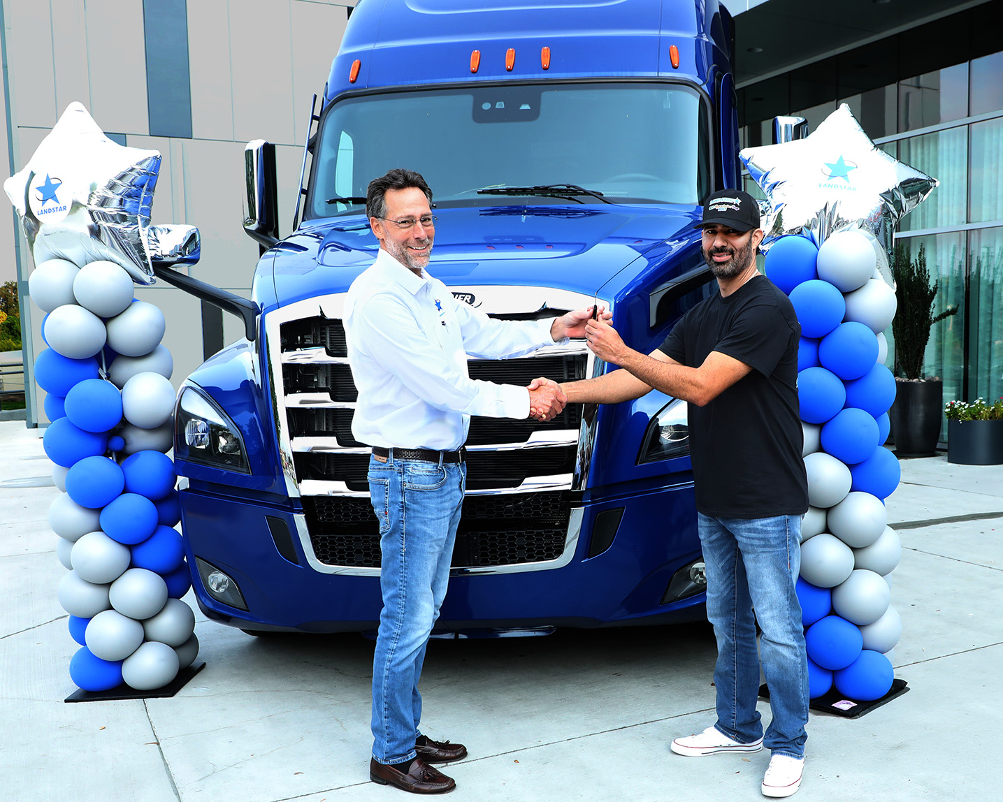 Landstar President and CEO Frank Lonegro, left, awards truck winner and Landstar owner-operator Christian Sanchez Cant&ugrave; with the keys to his new rig.