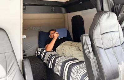 Kovalenko taking a well deserved break. He reconfigured the sleeper, placing the bunk lengthwise behind the driver’s seat of this Freightliner Cascadia. The bed was custom designed for his 5’10” height and, incidentally is just long enough for this 6’1” gearjammer (photo not included). According to Nataliia, other configurations are available to accommodate drivers up to 6’8”, with plenty custom variation depending on the truck. Find more via the Be Camper Sleeper website or social media.