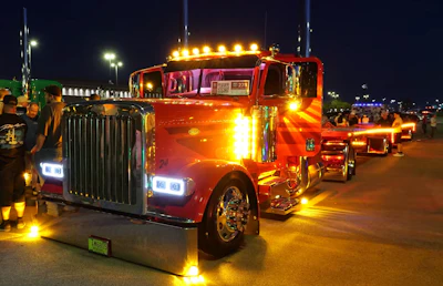 Up near the front end, custom adds include Peterbilt 379-style headlights, a bolt-less bumper, air-ride front end, air cleaner lights, visor lights, stainless wiper arms, Dynaflex stacks, cab and sleeper panels, battery box covers and mirror lights.