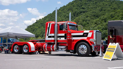 This 2009 Peterbilt 389, 'The Striped Truck,' is owned by Rob Wallace. It features a four-color Winslow paint scheme and is powered by a C15 Cat.