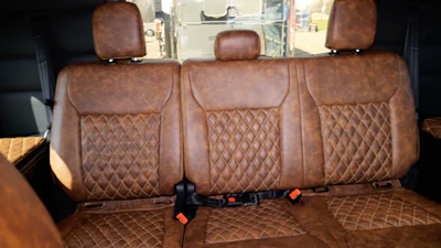 The bench is wrapped in leather to match the front seats. It’s also equipped with a refrigerator and 110-volt outlets on both sides.