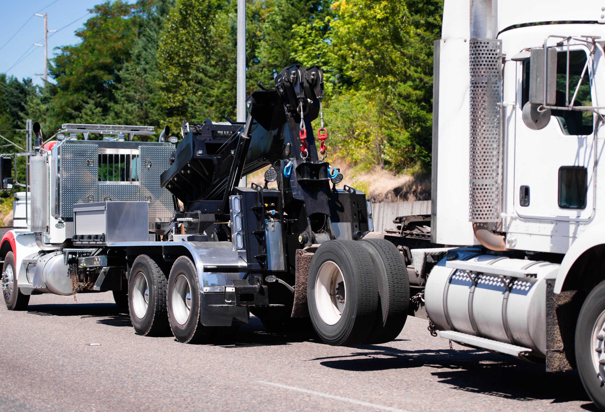 Heavy-duty industrial truck with hydraulic crane equipment transporting cargo on a sunny road