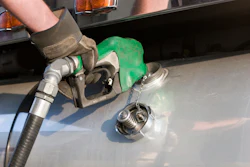 Green fuel pump nozzle inserted into vehicle fuel tank during refueling at gas station