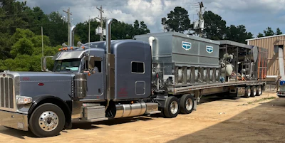 Gray Peterbilt semi-truck with Schmitz Cargobull livestock trailer parked at industrial facility