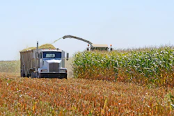 Combine harvester and grain truck harvesting corn in agricultural field