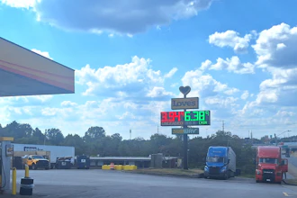 Love's Travel Stop gas station sign displaying fuel prices on a sunny day with blue sky and clouds