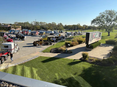 Aerial view of heavy equipment rental yard with machinery, vehicles, and green landscaping on sunny day