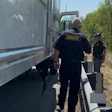 USDOT officials inspect a commercial truck on a rural roadside with trees in background