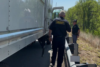 USDOT officials inspect a commercial truck on a rural roadside with trees in background