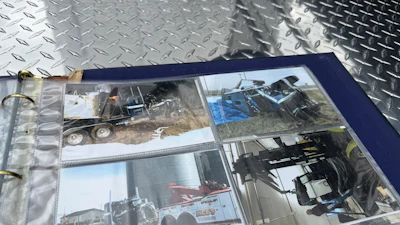 Photo album with construction equipment and machinery photographs displayed in navy binder on metal surface