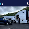 Law enforcement officer and commercial truck driver at roadside safety inspection checkpoint