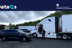 Law enforcement officer and commercial truck driver at roadside safety inspection checkpoint