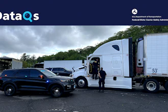Law enforcement officer and commercial truck driver at roadside safety inspection checkpoint