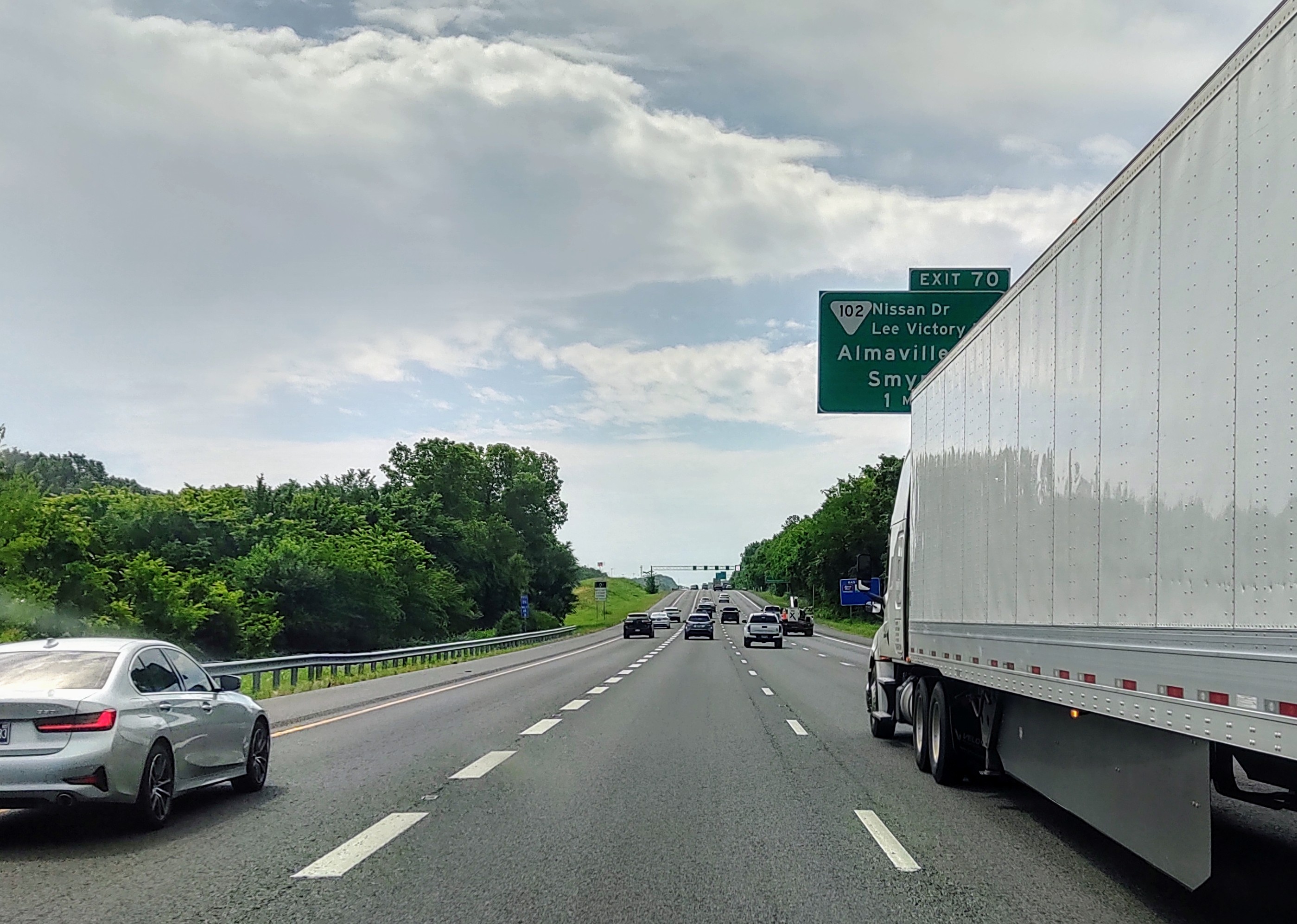 Highway traffic scene with vehicles and green exit sign for Nissan Drive and Almavilla on a cloudy day