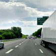 Highway traffic scene with vehicles and green exit sign for Nissan Drive and Almavilla on a cloudy day