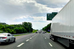 Highway traffic scene with vehicles and green exit sign for Nissan Drive and Almavilla on a cloudy day