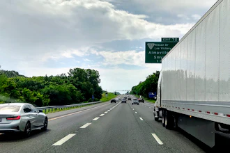 Highway traffic scene with vehicles and green exit sign for Nissan Drive and Almavilla on a cloudy day
