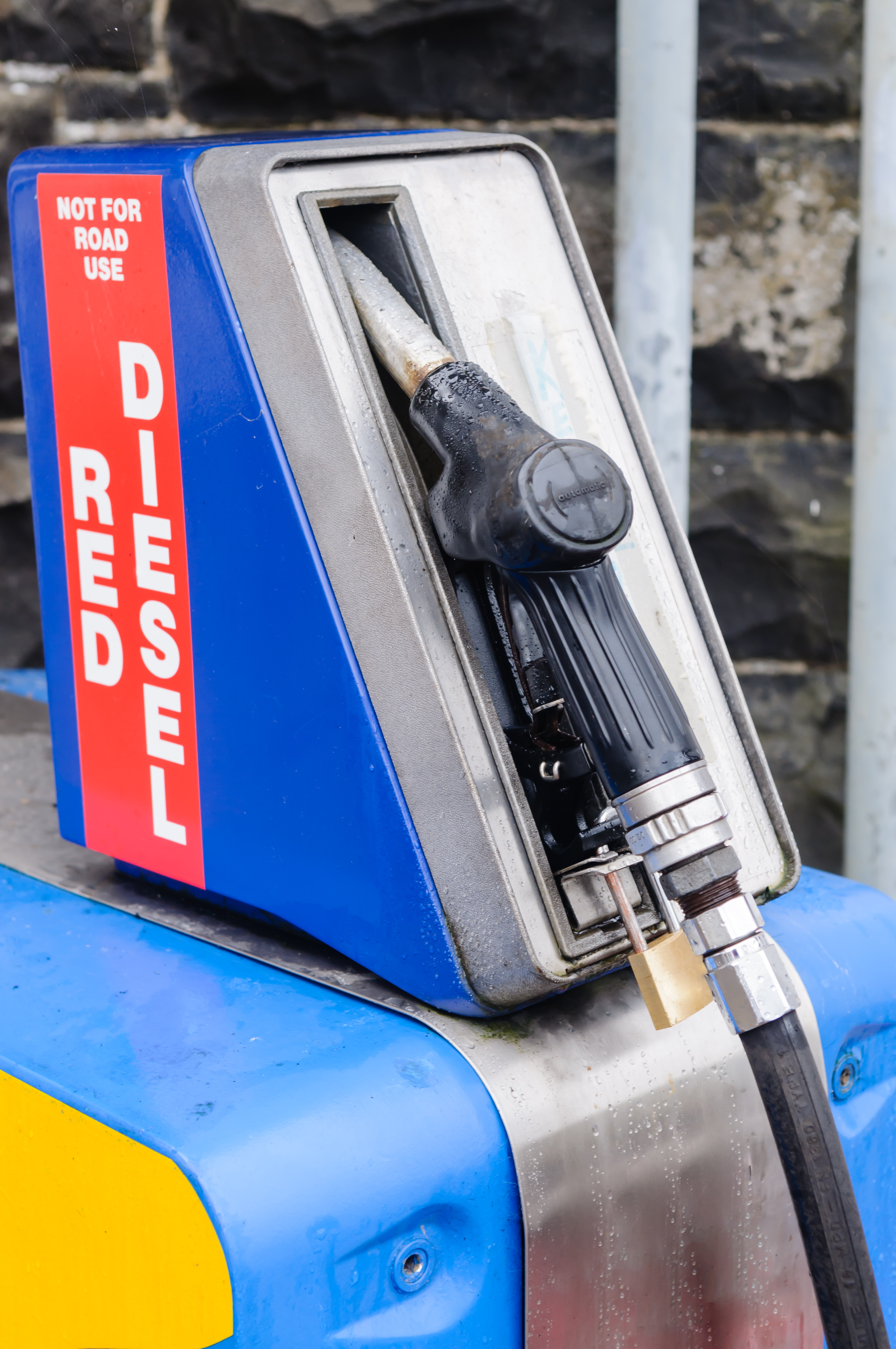 Vintage diesel fuel pump dispenser with blue housing and red warning label mounted on yellow base