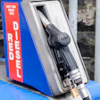 Vintage diesel fuel pump dispenser with blue housing and red warning label mounted on yellow base