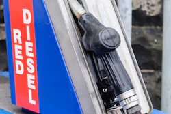 Vintage diesel fuel pump dispenser with blue housing and red warning label mounted on yellow base