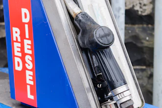 Vintage diesel fuel pump dispenser with blue housing and red warning label mounted on yellow base