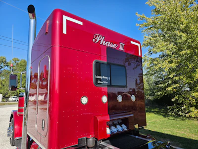 Red Phase II food truck parked outdoors with trees and clear sky in background