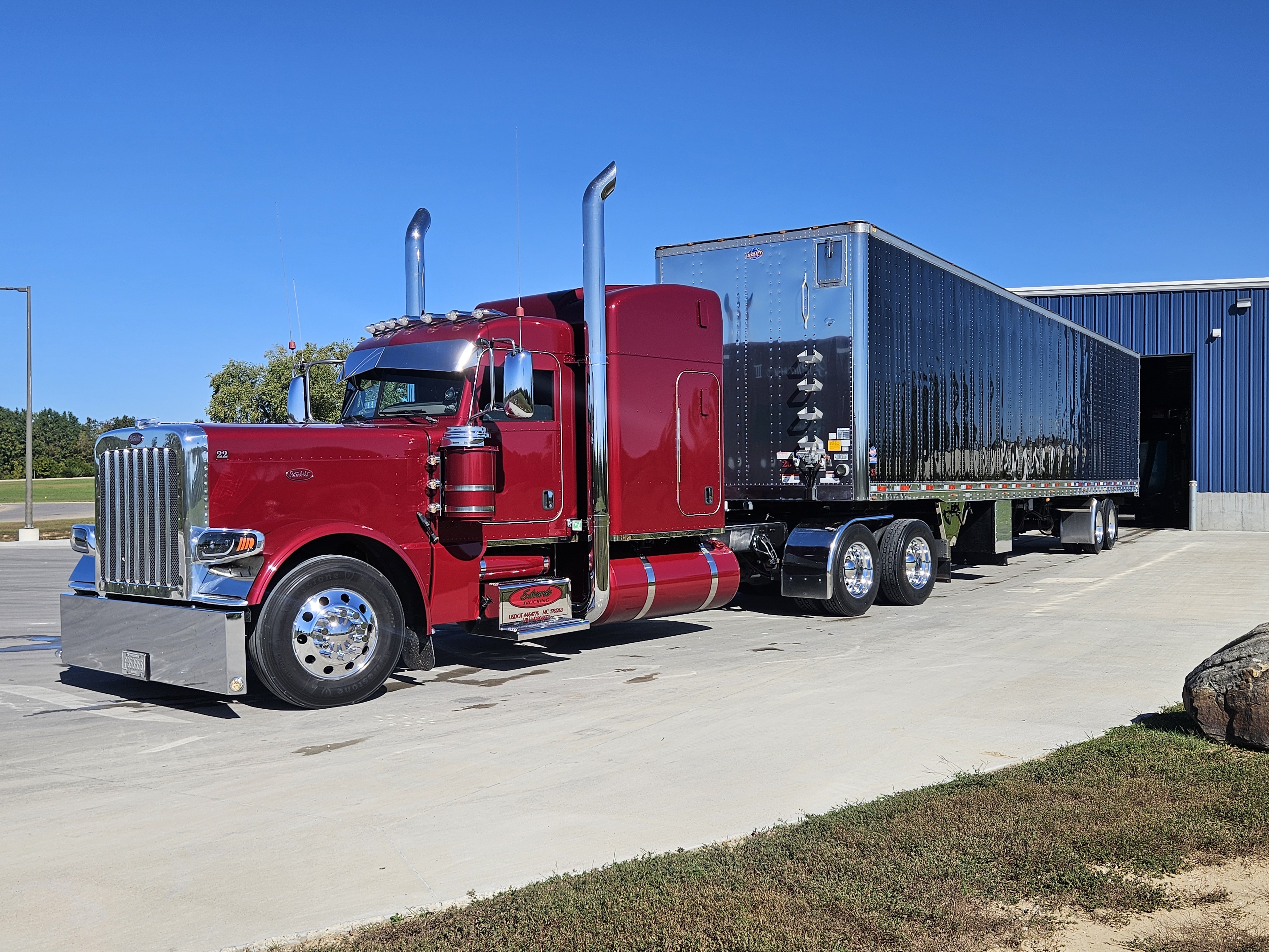 Red Peterbilt semi-truck with custom black enclosed trailer parked in lot