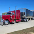 Red Peterbilt semi-truck with custom black enclosed trailer parked in lot