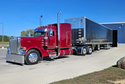 Red Peterbilt semi-truck with custom black enclosed trailer parked in lot