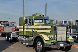 Green and cream Peterbilt semi-truck with dual exhaust stacks displayed at outdoor truck show