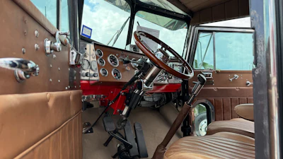 Classic truck interior with brown dashboard, steering wheel, and red bench seat