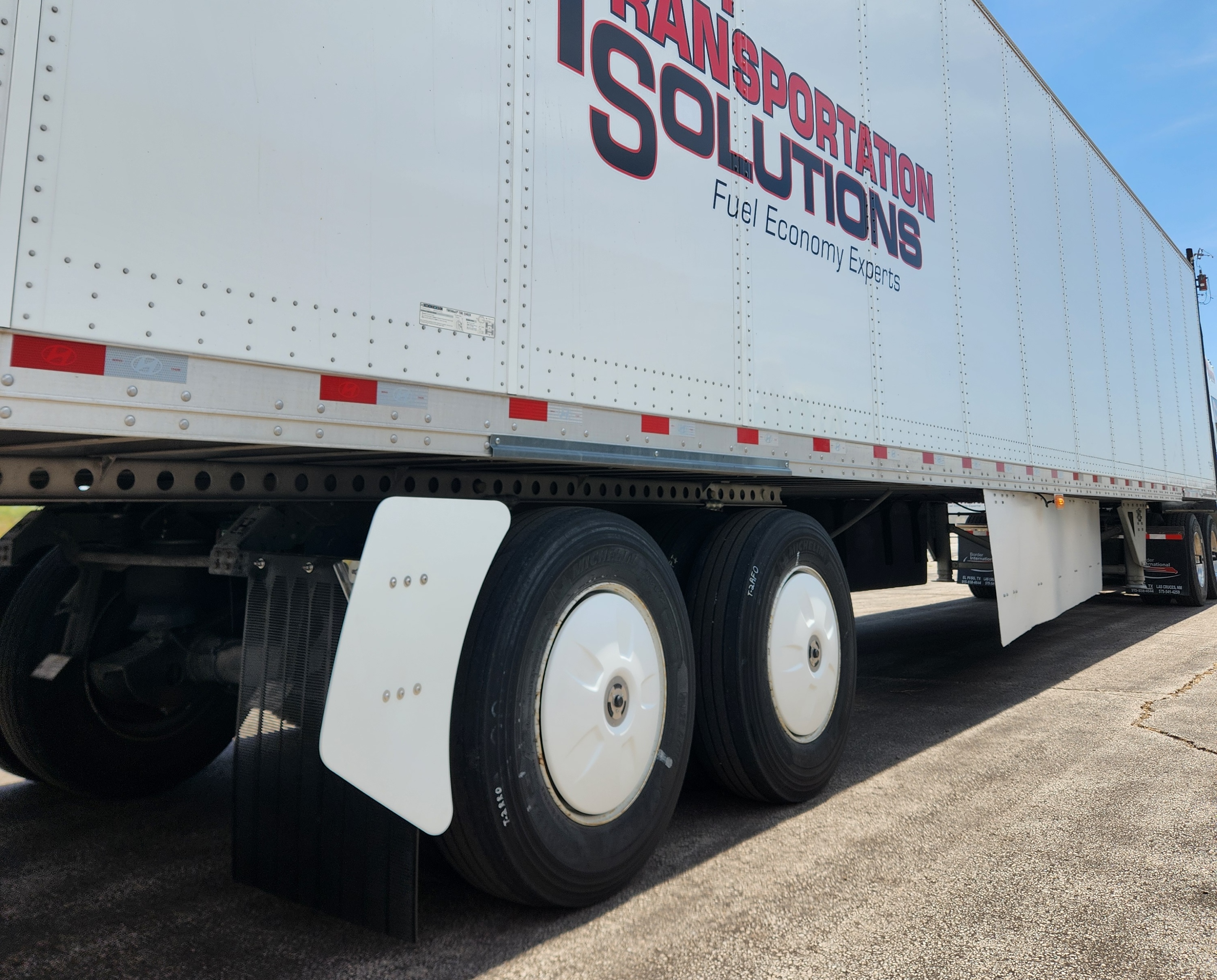 White semi-truck trailer with red and black Transportation Solutions branding and Fuel Economy Experts tagline