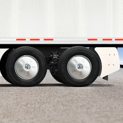 Close-up of commercial truck dual rear wheels with silver hubcaps and black tires on asphalt