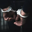 Person wearing handcuffs with hands restrained in dark lighting