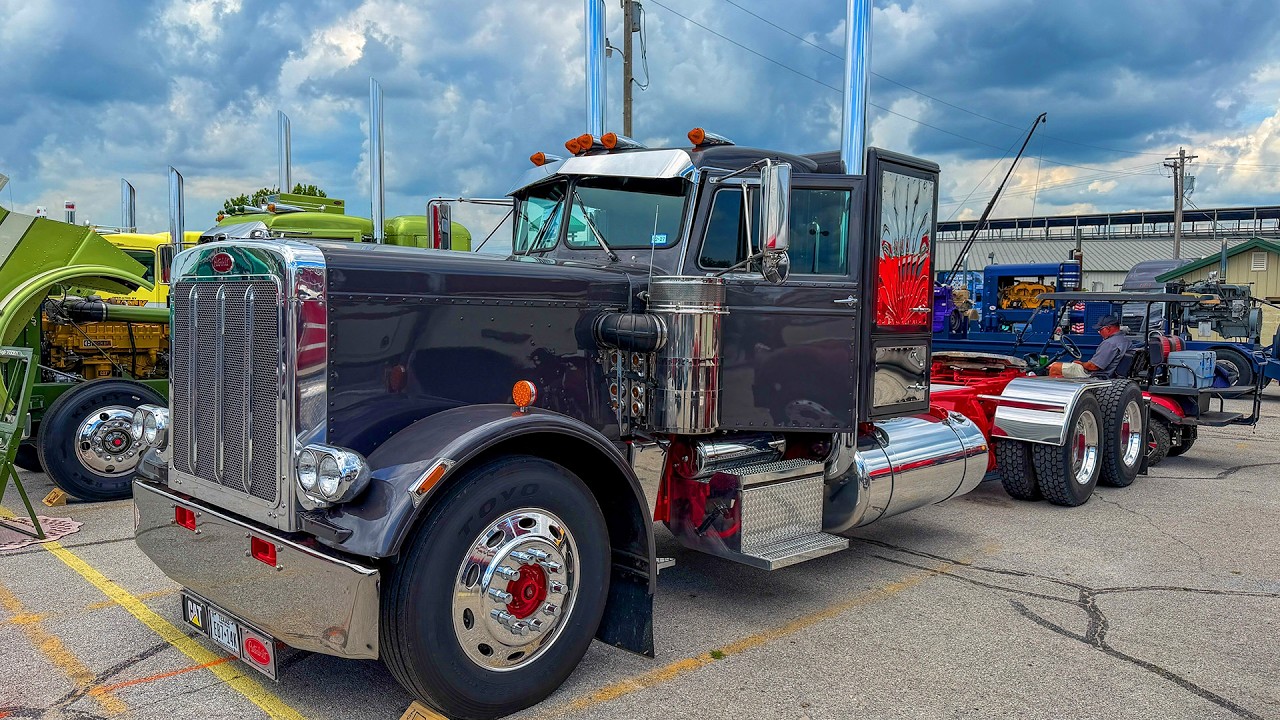 Vintage black semi-truck with chrome details and orange lights displayed at outdoor truck show
