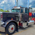 Vintage black semi-truck with chrome details and orange lights displayed at outdoor truck show