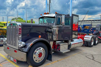 Vintage black semi-truck with chrome details and orange lights displayed at outdoor truck show
