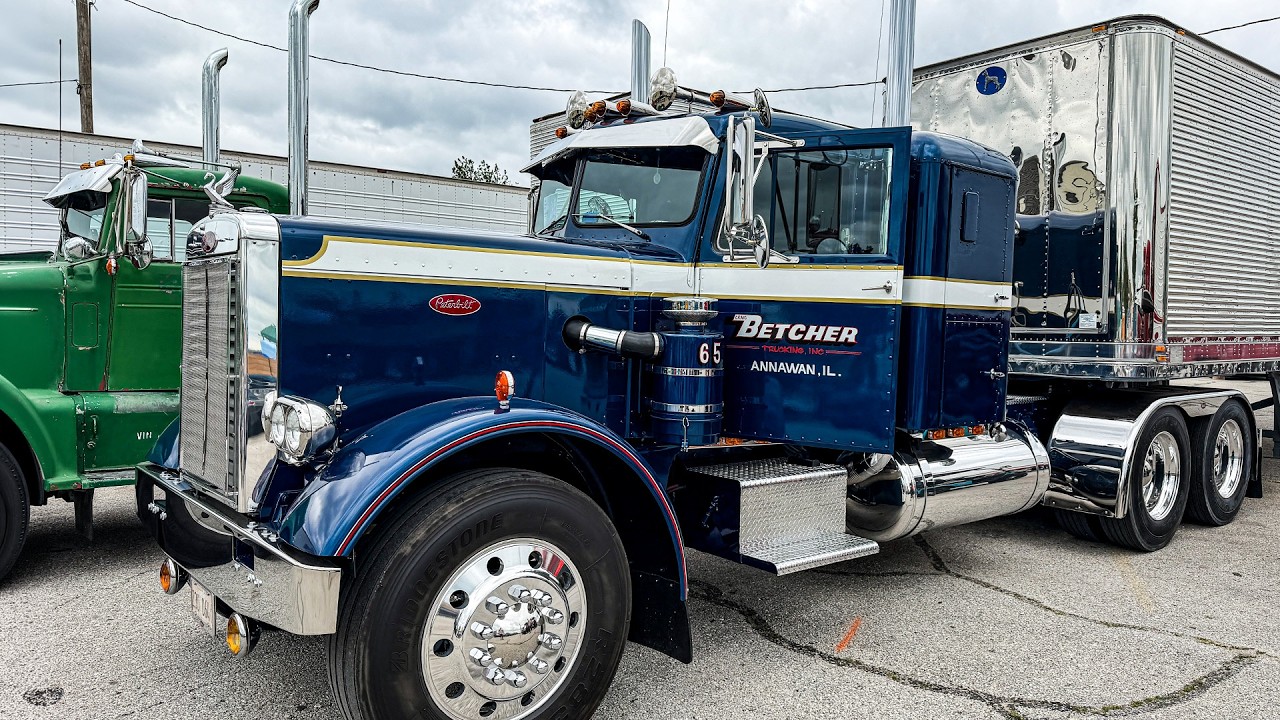 Vintage navy blue Peterbilt semi-truck with Betcher branding parked at an industrial lot